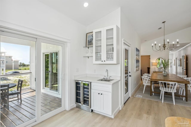 bar with wine cooler, white cabinetry, vaulted ceiling, and sink