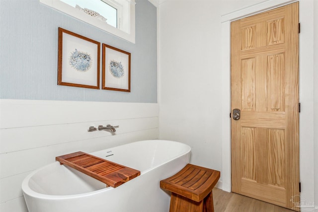 bathroom with wood-type flooring and a bath