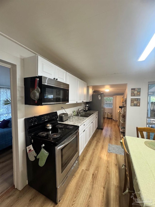 kitchen featuring sink, white cabinetry, stainless steel appliances, and light hardwood / wood-style flooring