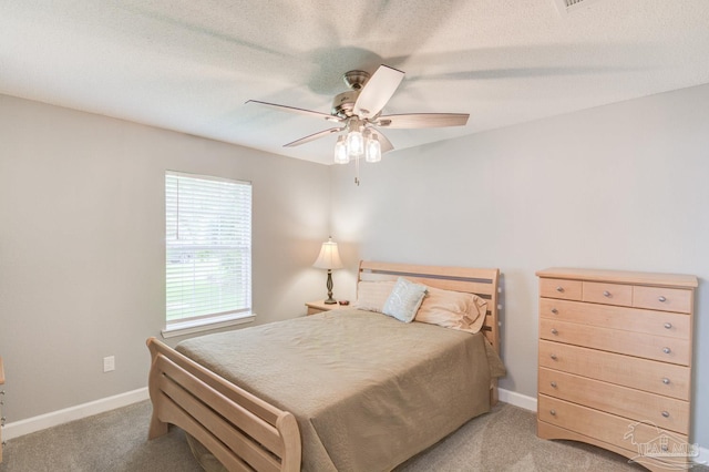 carpeted bedroom with ceiling fan and a textured ceiling