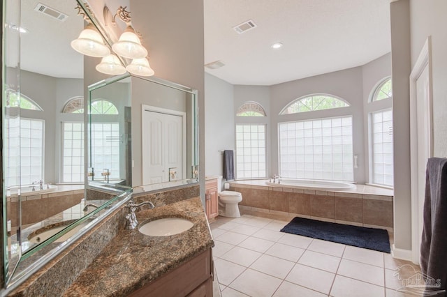 bathroom featuring tile patterned floors, vanity, tiled tub, and toilet