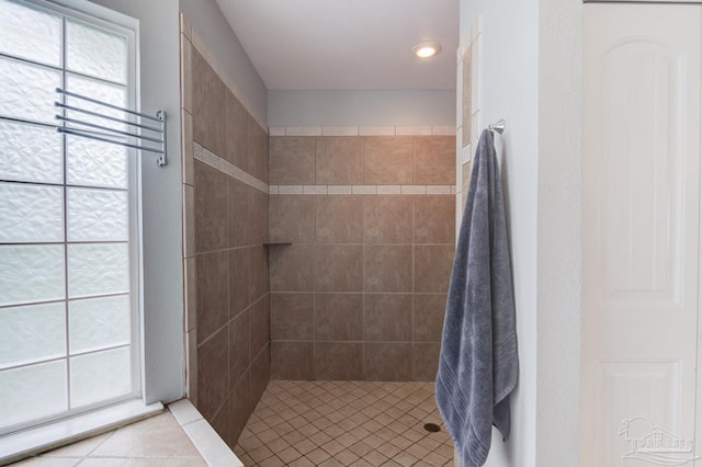 bathroom with tile patterned flooring, a healthy amount of sunlight, and tiled shower