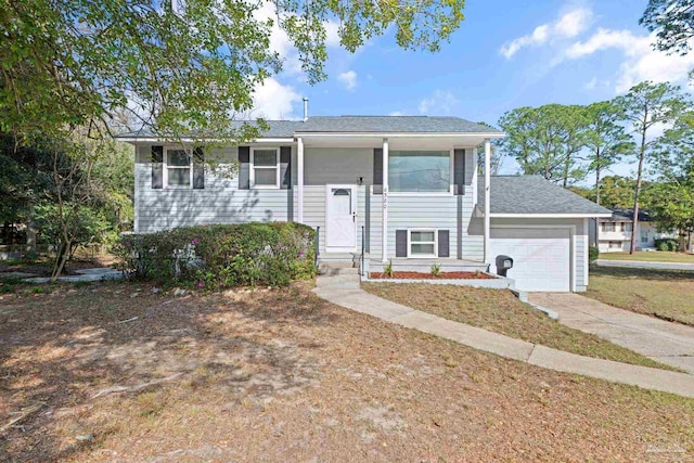 raised ranch with concrete driveway, a garage, and a shingled roof