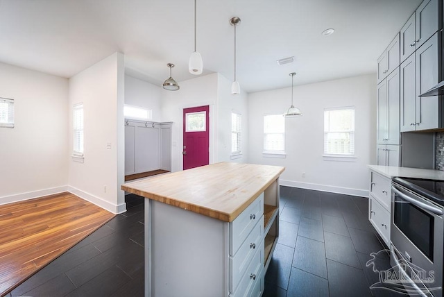 kitchen with wooden counters, stainless steel range with electric stovetop, a center island, decorative light fixtures, and dark hardwood / wood-style flooring