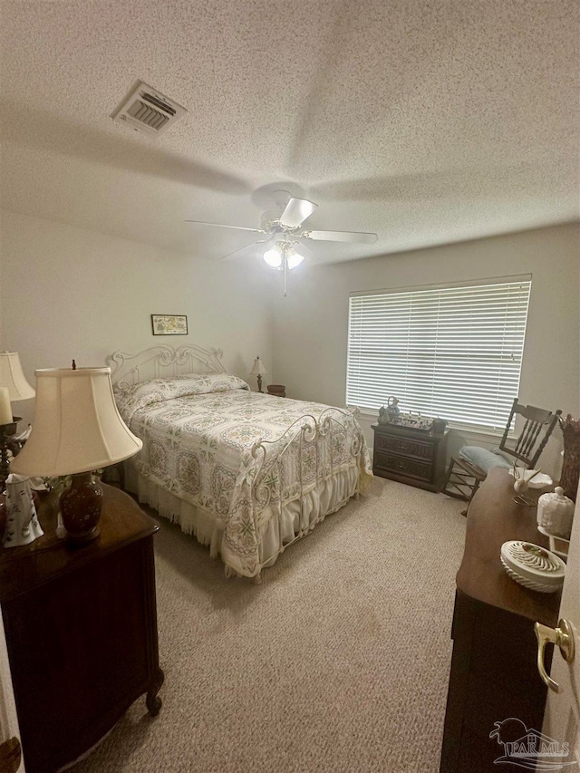 bedroom featuring a textured ceiling, light colored carpet, and ceiling fan