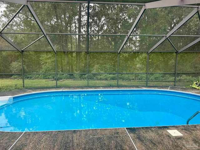 view of swimming pool featuring glass enclosure