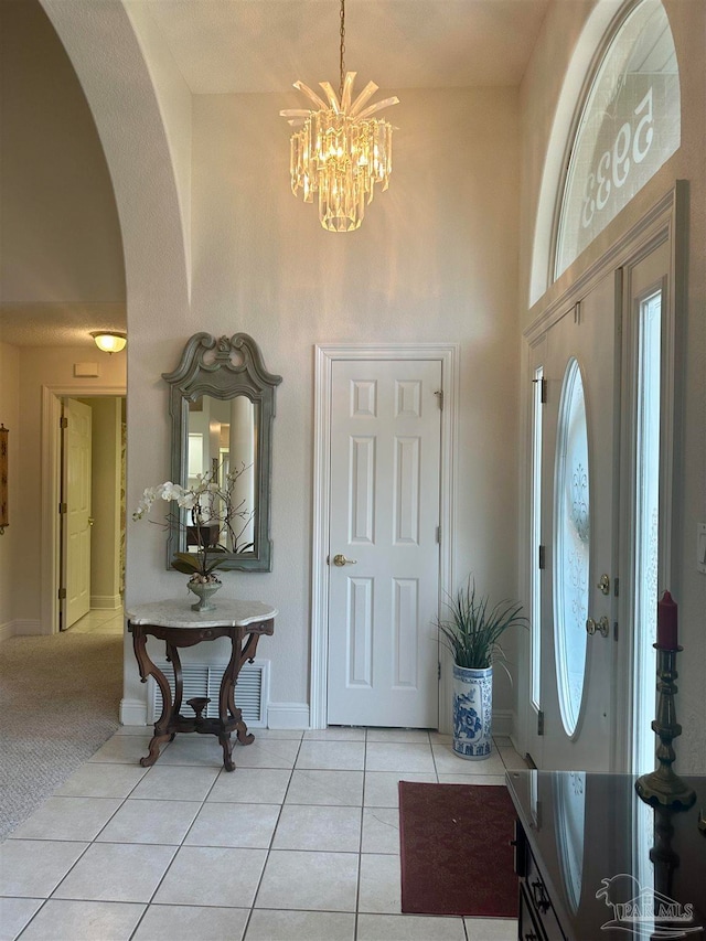 tiled entrance foyer with high vaulted ceiling and a chandelier