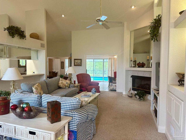 living room featuring high vaulted ceiling, light colored carpet, ceiling fan, and a tile fireplace