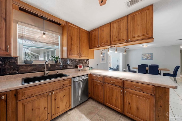 kitchen featuring sink, tasteful backsplash, hanging light fixtures, dishwasher, and kitchen peninsula