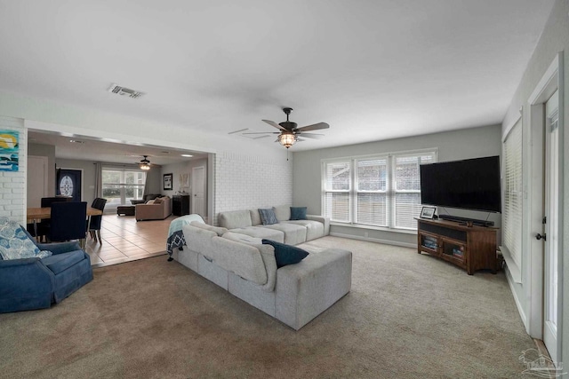 living room with brick wall, ceiling fan, and carpet flooring