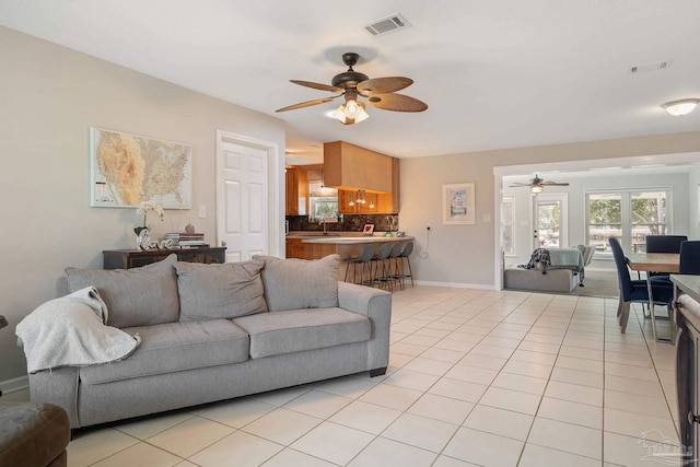 tiled living room with ceiling fan and sink