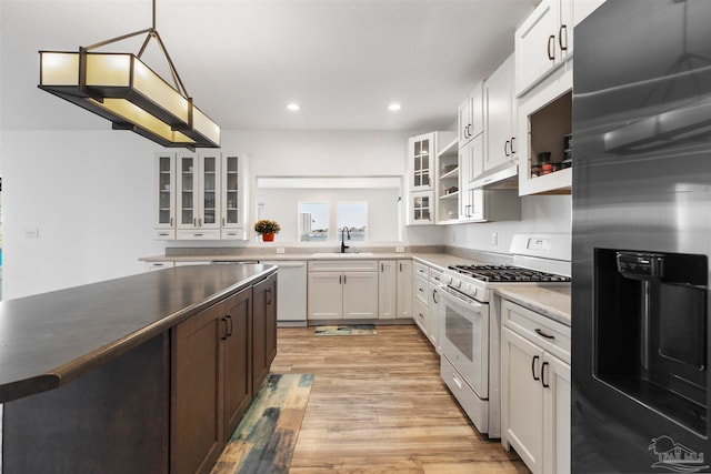 kitchen with white cabinetry, light hardwood / wood-style floors, decorative light fixtures, sink, and white appliances