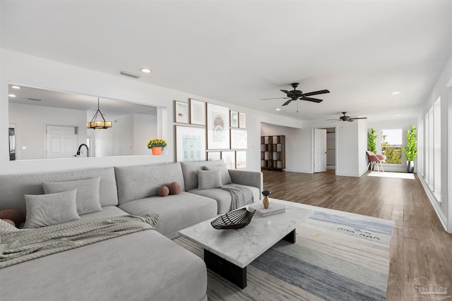 living room with a healthy amount of sunlight, hardwood / wood-style flooring, and ceiling fan with notable chandelier