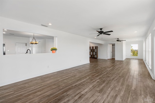 unfurnished living room with dark hardwood / wood-style flooring and ceiling fan with notable chandelier