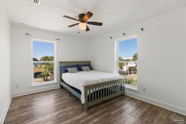 bedroom featuring dark hardwood / wood-style flooring, multiple windows, and ceiling fan