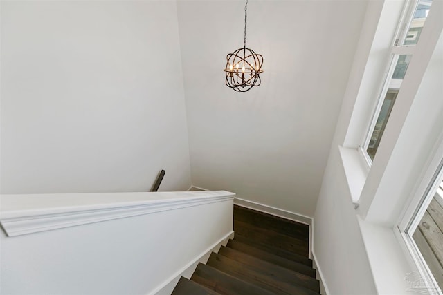 stairs featuring a wealth of natural light, hardwood / wood-style floors, and an inviting chandelier