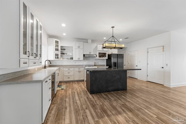 kitchen featuring black refrigerator with ice dispenser, white cabinets, a kitchen island, light hardwood / wood-style floors, and decorative light fixtures