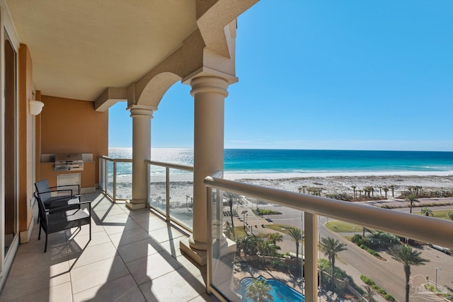 balcony with a water view and a view of the beach