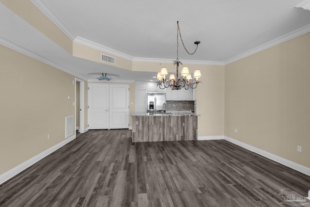 unfurnished dining area featuring ornamental molding, dark hardwood / wood-style flooring, an inviting chandelier, and a tray ceiling