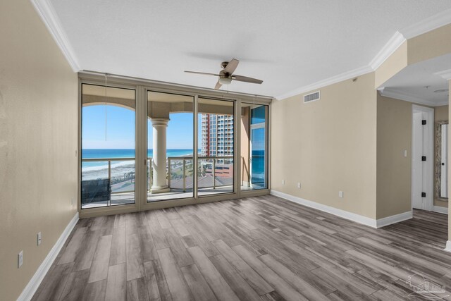 unfurnished room with ornamental molding, ceiling fan, a water view, and hardwood / wood-style floors