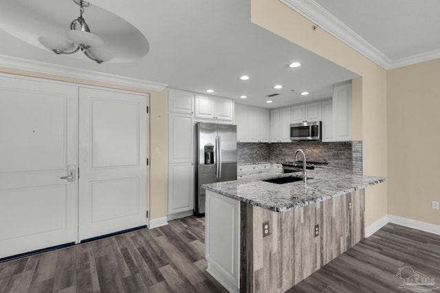 kitchen with appliances with stainless steel finishes, crown molding, sink, white cabinetry, and decorative light fixtures