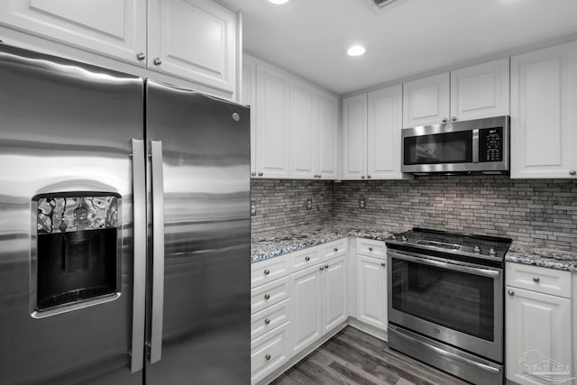 kitchen featuring white cabinetry, light stone counters, tasteful backsplash, dark hardwood / wood-style floors, and appliances with stainless steel finishes