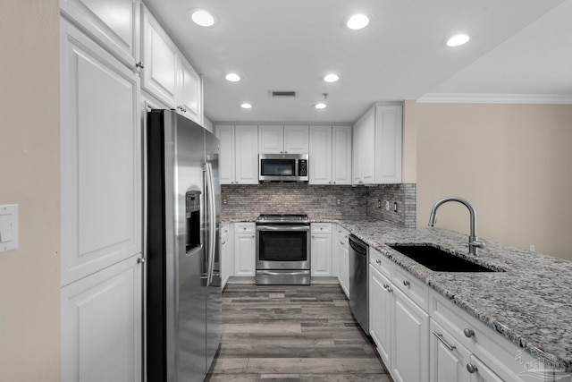 kitchen featuring stainless steel appliances, white cabinetry, sink, and backsplash