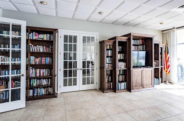 misc room with a paneled ceiling, french doors, and light tile patterned flooring