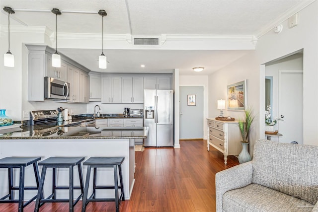 kitchen with gray cabinets, appliances with stainless steel finishes, kitchen peninsula, and decorative light fixtures