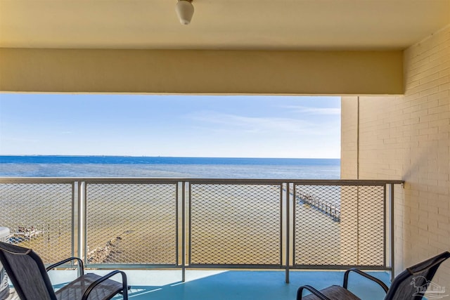 balcony featuring ceiling fan, a water view, and a beach view