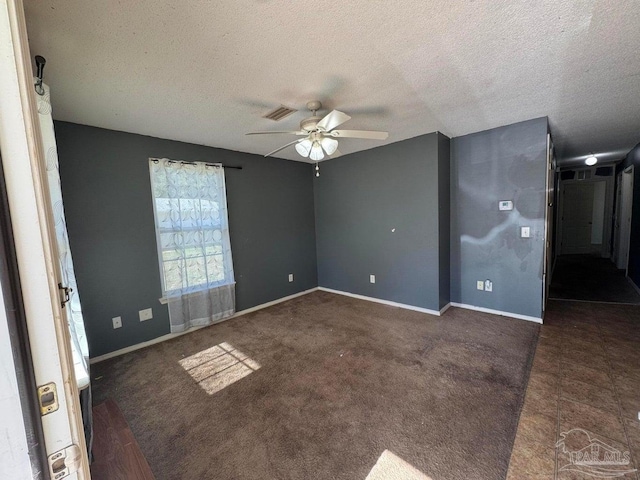 empty room featuring a textured ceiling, ceiling fan, baseboards, and carpet