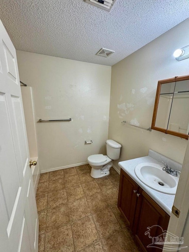 bathroom with a textured ceiling, vanity, toilet, and baseboards