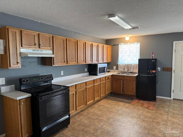 kitchen with black appliances, under cabinet range hood, a sink, brown cabinets, and light countertops