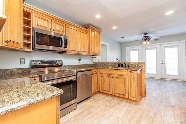 kitchen with kitchen peninsula, french doors, stainless steel appliances, ceiling fan, and sink