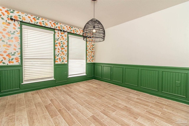 empty room with light hardwood / wood-style flooring and a notable chandelier