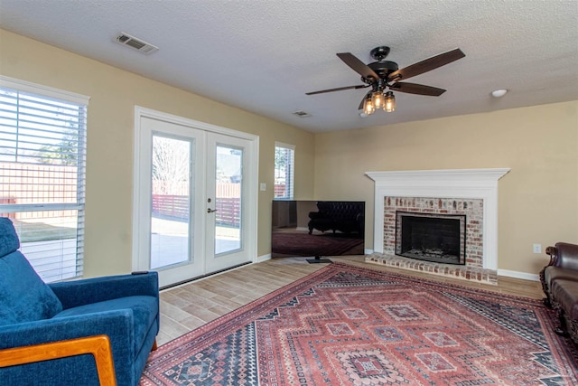 living room with ceiling fan, wood-type flooring, a textured ceiling, and french doors