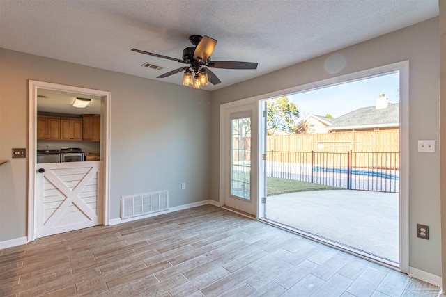 doorway with ceiling fan, washer and clothes dryer, and a textured ceiling