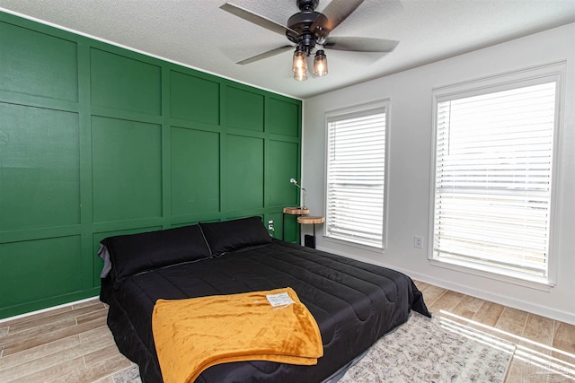 bedroom with ceiling fan, a textured ceiling, and light wood-type flooring