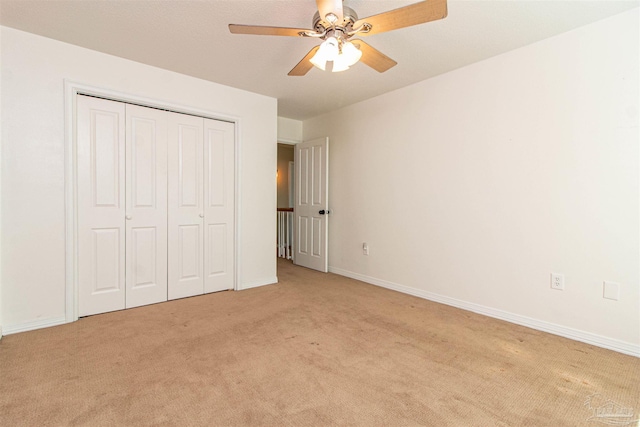 unfurnished bedroom featuring ceiling fan, a closet, and light carpet