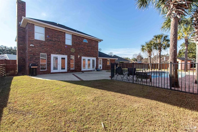 back of house featuring french doors, a yard, a fenced in pool, and a patio area