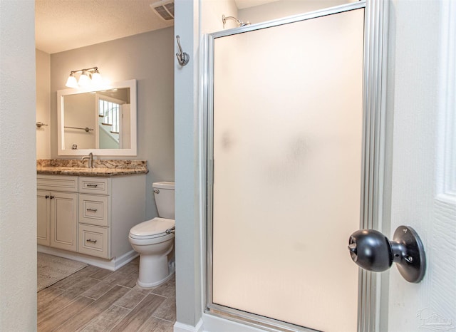 bathroom with a textured ceiling, vanity, toilet, and walk in shower