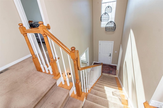 stairway with carpet and a high ceiling