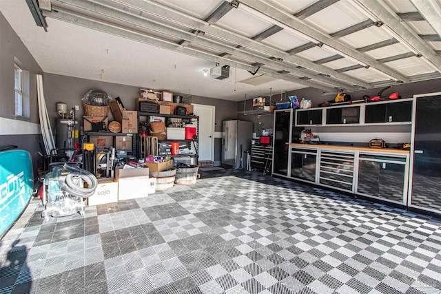 garage featuring white fridge, a garage door opener, and water heater