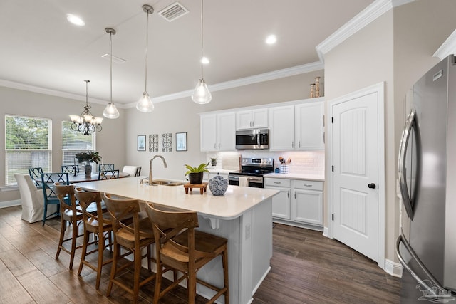 kitchen with visible vents, a kitchen island with sink, a breakfast bar area, a sink, and stainless steel appliances
