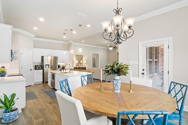 dining space featuring ornamental molding, ceiling fan with notable chandelier, light wood-type flooring, and visible vents