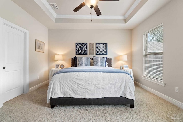 carpeted bedroom featuring ceiling fan, visible vents, crown molding, a raised ceiling, and baseboards