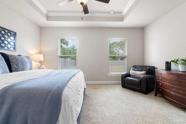 carpeted bedroom with crown molding, a tray ceiling, ceiling fan, and baseboards