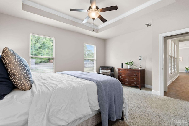 bedroom featuring crown molding, a tray ceiling, visible vents, and baseboards