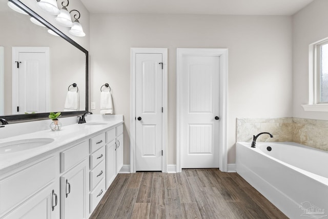 bathroom featuring double vanity, a sink, a garden tub, and wood finished floors
