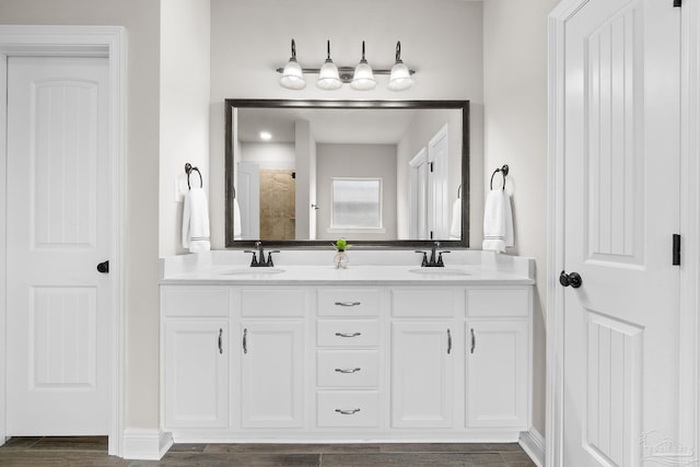 full bathroom with double vanity, a sink, wood finished floors, and a tile shower